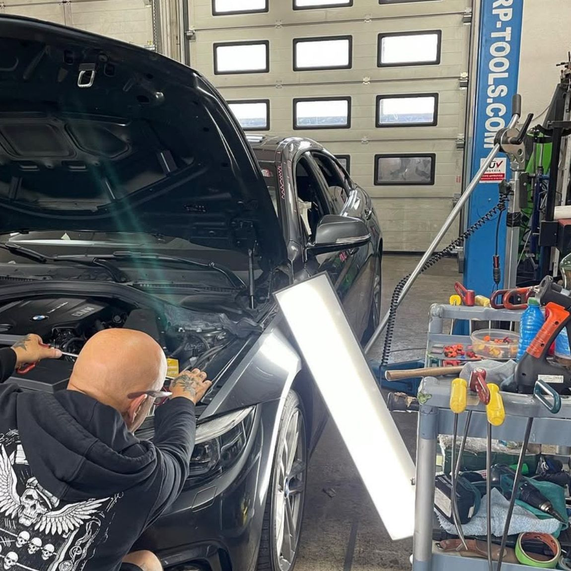 Ausbeulen eines Hagelschadens an einem BMW mit Lichtleiste zur Kontrolle der Oberfläche