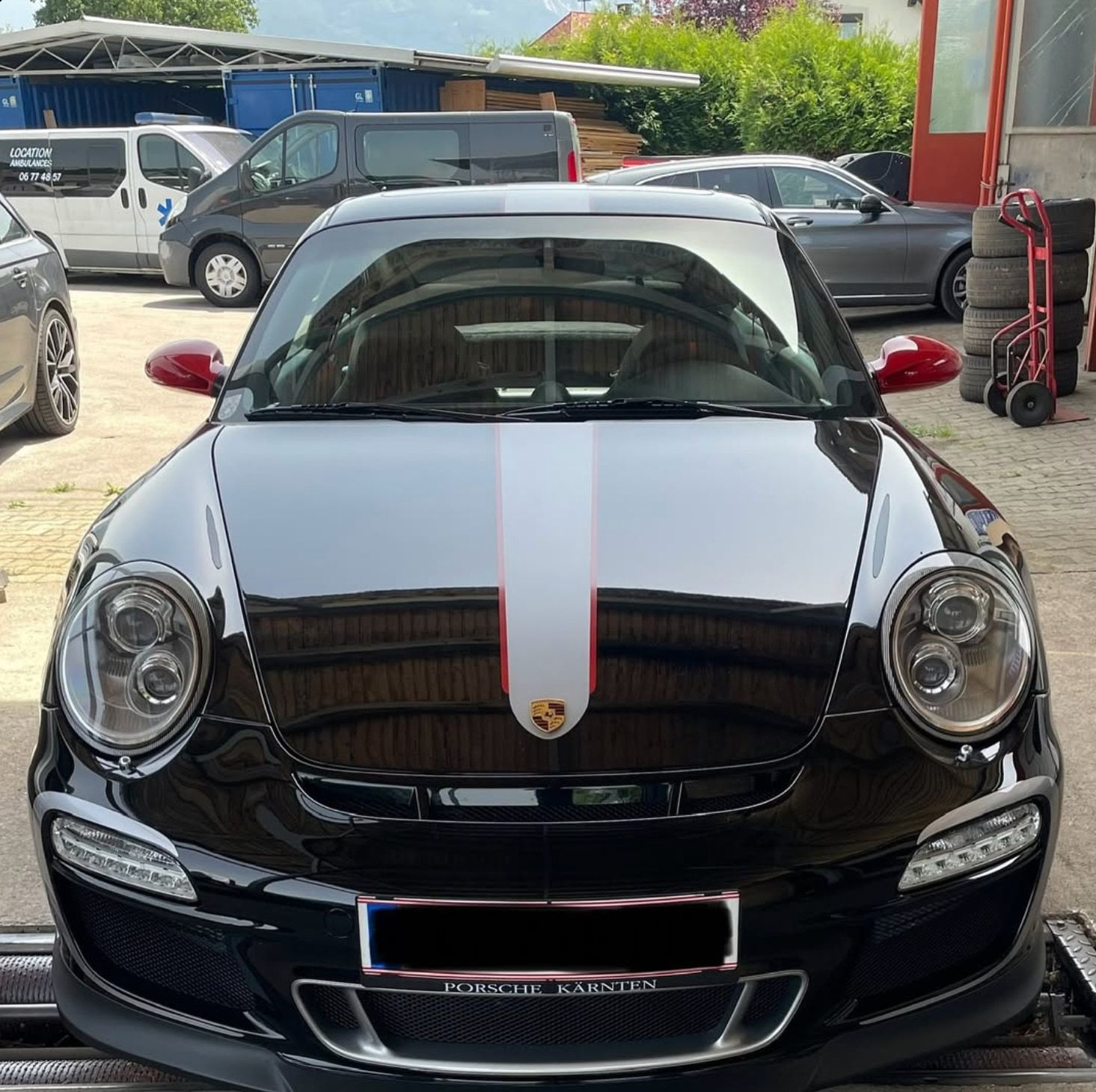 Schwarzer Porsche 911 Carrera der Baureihe 997 mit Mittelstreifen auf der Hebebühne