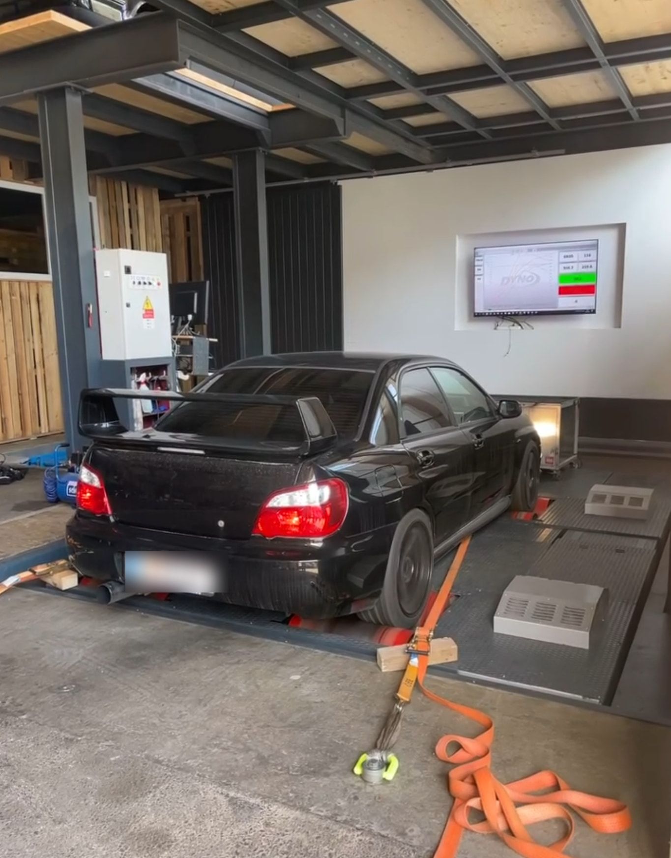 Subaru Impreza auf einem Leistungsprüfstand, Bildschirm mit Messkurve im Hintergrund